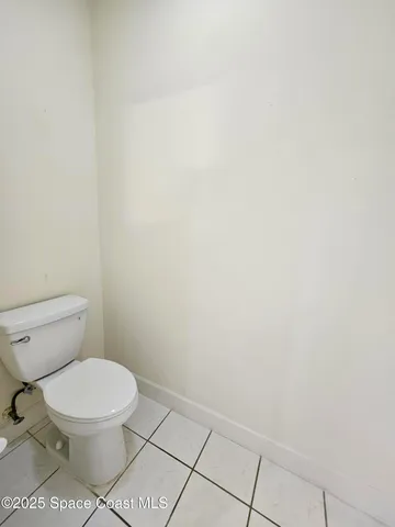 a white toilet sitting next to a white wall