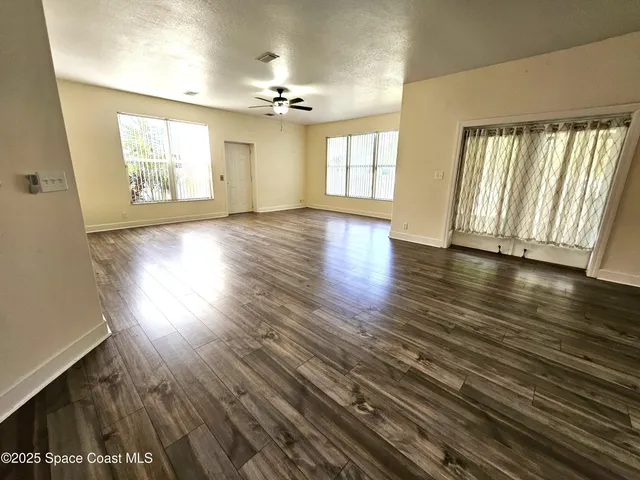 an empty room with wooden floor and windows