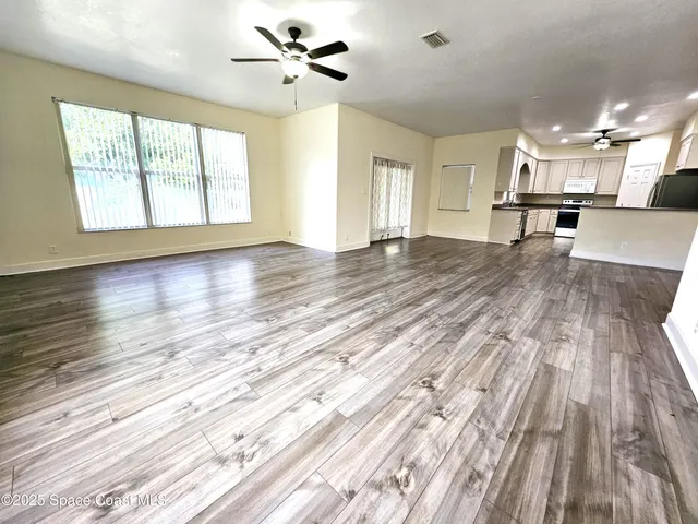 a view of empty room with wooden floor and fan