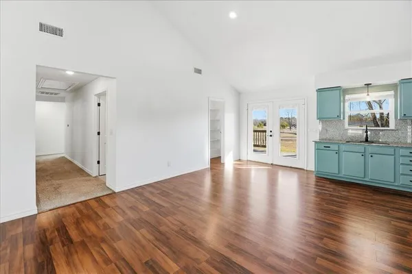 a view of an empty room with window and wooden floor