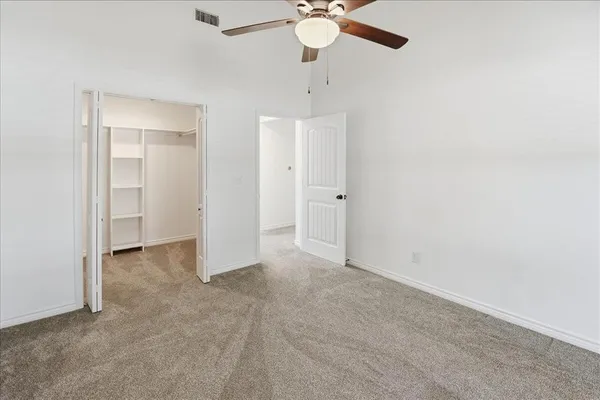 an empty room with a chandelier fan and closet