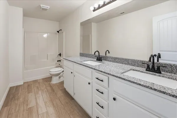 a bathroom with a granite countertop sink a toilet and a bathtub