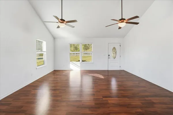 a view of empty room with wooden floor and fan