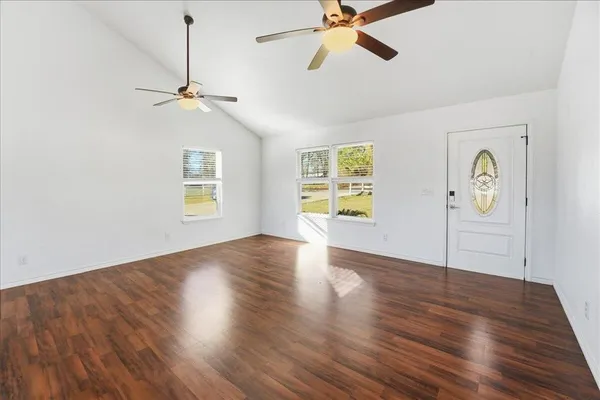 a view of empty room with wooden floor and fan