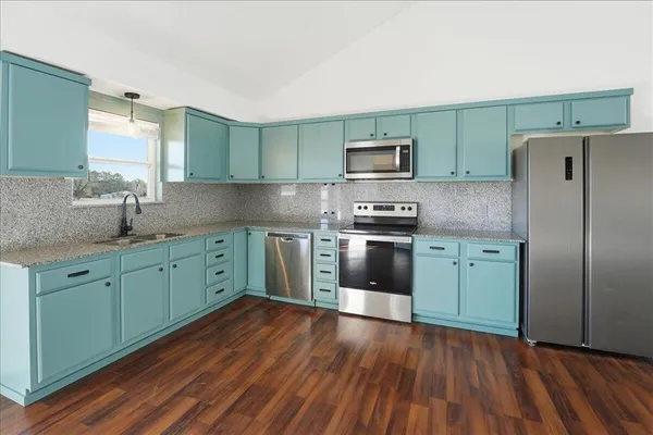 a kitchen with stainless steel appliances granite countertop a sink cabinets and wooden floor