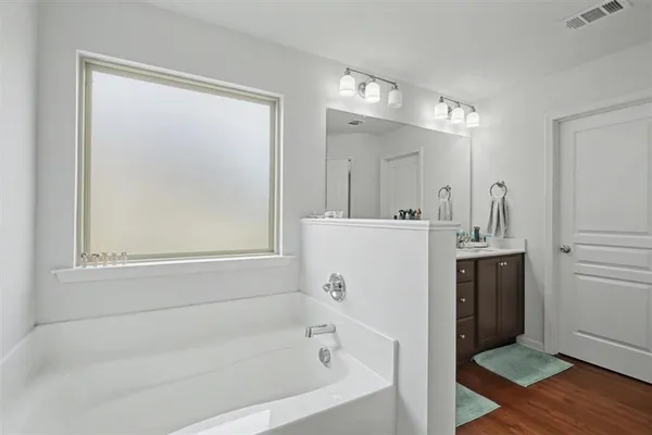 a bathroom with a bathtub a mirror a vanity and a shower