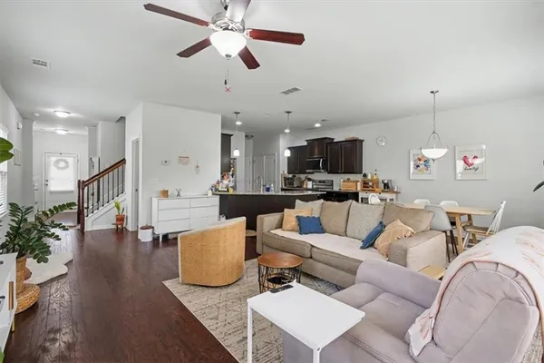a living room with furniture kitchen view and a wooden floor