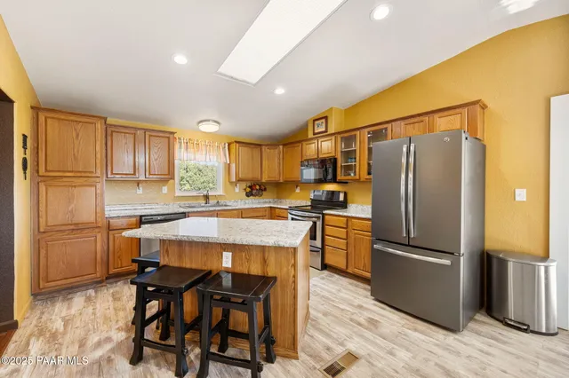 a kitchen with a refrigerator a microwave oven a sink and a dining table with wooden floor