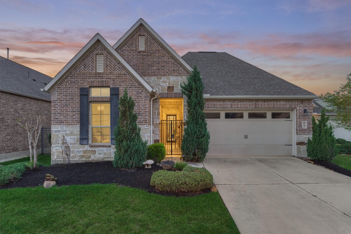 Stunning brick and stone elevation with exceptional curb appeal! This beautifully maintained home welcomes you with a gated front courtyard entry, lush landscaping, and a warm, inviting glow. The charming architectural details, manicured lawn, and private front entry create a perfect first impression of elegance and coMfort