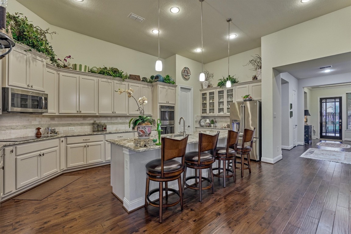 7430 Kearney Hill Lane Spring, TX 77389 - Photo 11 of 47 Spacious chef’s kitchen featuring an oversized island with seating, granite countertops, and abundant cabinetry. High ceilings, pendant lighting, and an open layout create a bright and inviting space perfect for everyday living and entertaining.