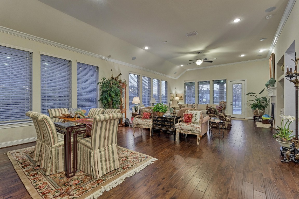 7430 Kearney Hill Lane Spring, TX 77389 - Photo 13 of 47 Open-concept living and dining area with expansive windows, rich wood flooring, and abundant natural light throughout. This spacious layout offers seamless flow and beautiful backyard views, perfect for both everyday living and entertaining.