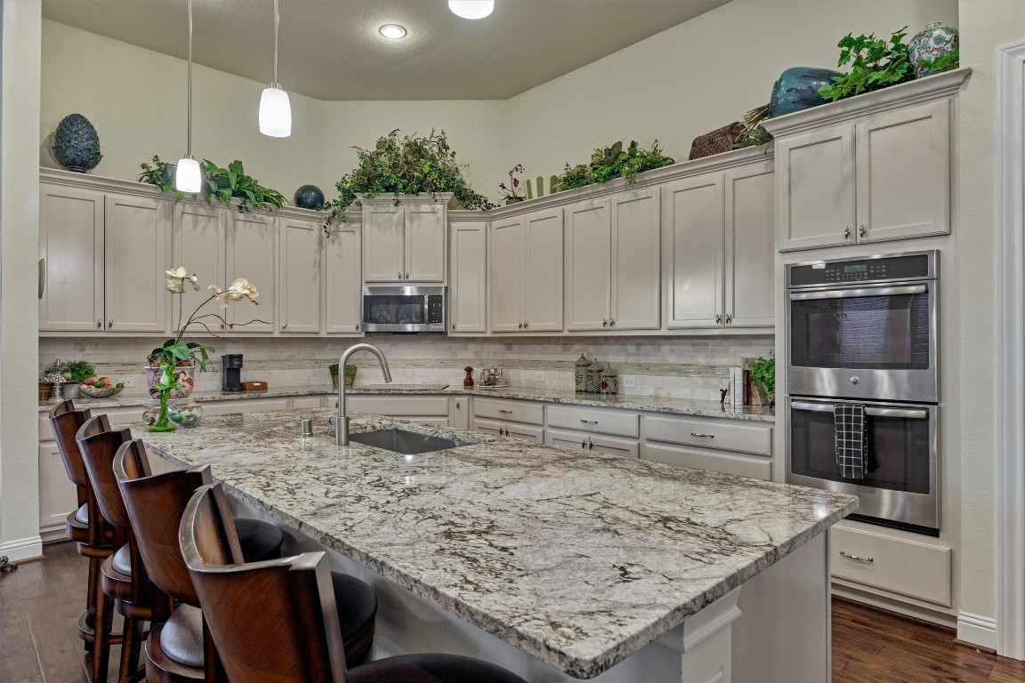 7430 Kearney Hill Lane Spring, TX 77389 - Photo 16 of 47 Gourmet kitchen featuring a large granite island with seating, double ovens, and extensive cabinetry for storage. High ceilings and modern finishes create a bright, open space perfect for cooking and entertaining.