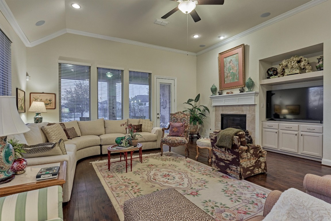 7430 Kearney Hill Lane Spring, TX 77389 - Photo 20 of 47 Cozy living room with a fireplace, built-in entertainment center, and large windows that fill the space with natural light. High ceilings and an open layout create a warm and inviting atmosphere perfect for relaxing or entertaining.