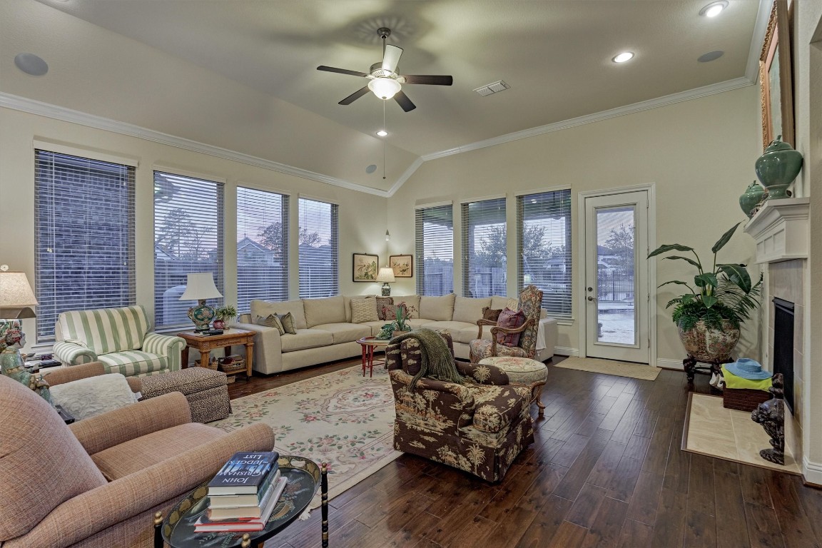 7430 Kearney Hill Lane Spring, TX 77389 - Photo 21 of 47 Bright and spacious living room featuring high ceilings, a cozy fireplace, and a wall of windows overlooking the backyard. The open layout and abundant natural light create a warm, inviting space ideal for relaxing or entertaining.