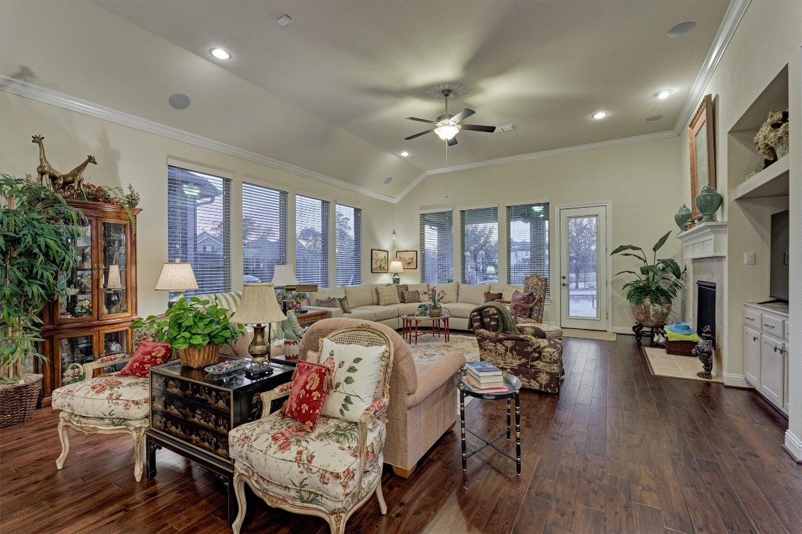7430 Kearney Hill Lane Spring, TX 77389 - Photo 23 of 47 Spacious living area with high ceilings, wood flooring, and a wall of windows providing beautiful natural light and backyard views. Features a cozy fireplace and open layout, perfect for comfortable living and entertaining
