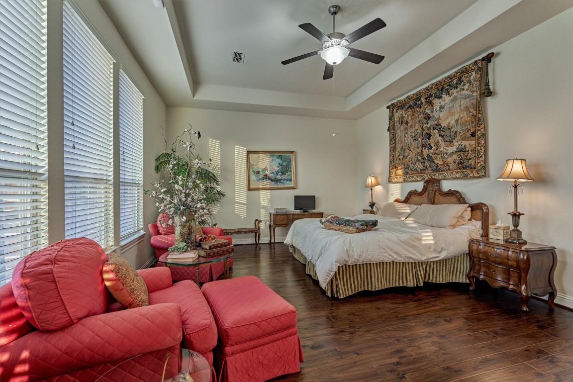 7430 Kearney Hill Lane Spring, TX 77389 - Photo 24 of 47 Spacious primary suite featuring engineered wood flooring, tray ceilings, and large windows that fill the room with natural light. Offers a comfortable sitting area and a serene, inviting atmosphere perfect for relaxation