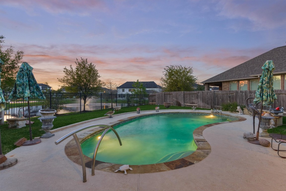 7430 Kearney Hill Lane Spring, TX 77389 - Photo 3 of 47 Resort-style pool with ambient lighting creates a relaxing backyard retreat perfect for evening enjoyment. Backing to a peaceful pond, this outdoor space offers scenic views and a tranquil setting for entertaining or unwinding