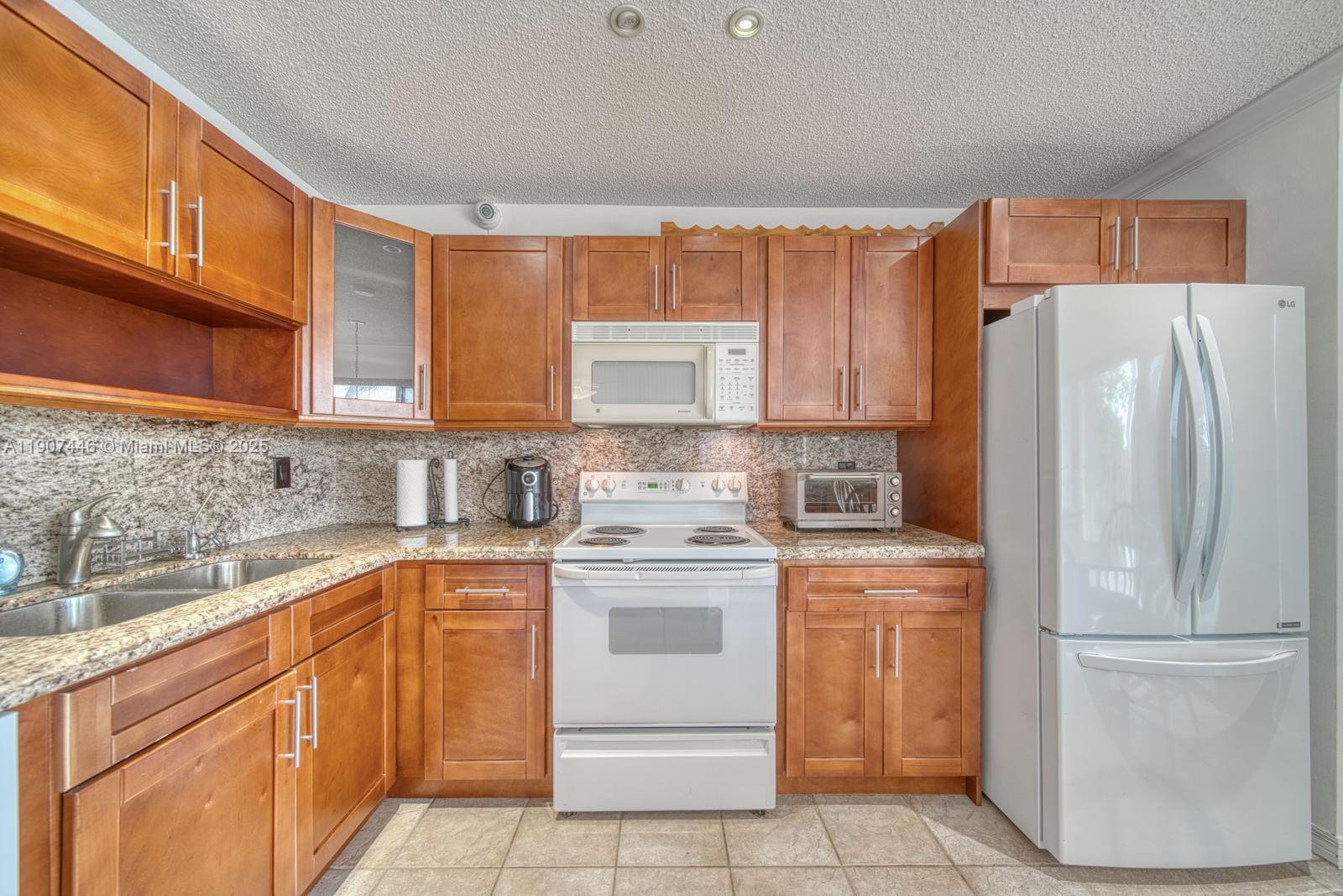 16394 Southwest 75th Street Miami, FL 33193 - Photo 12 of 35 a kitchen with a stove sink and refrigerator