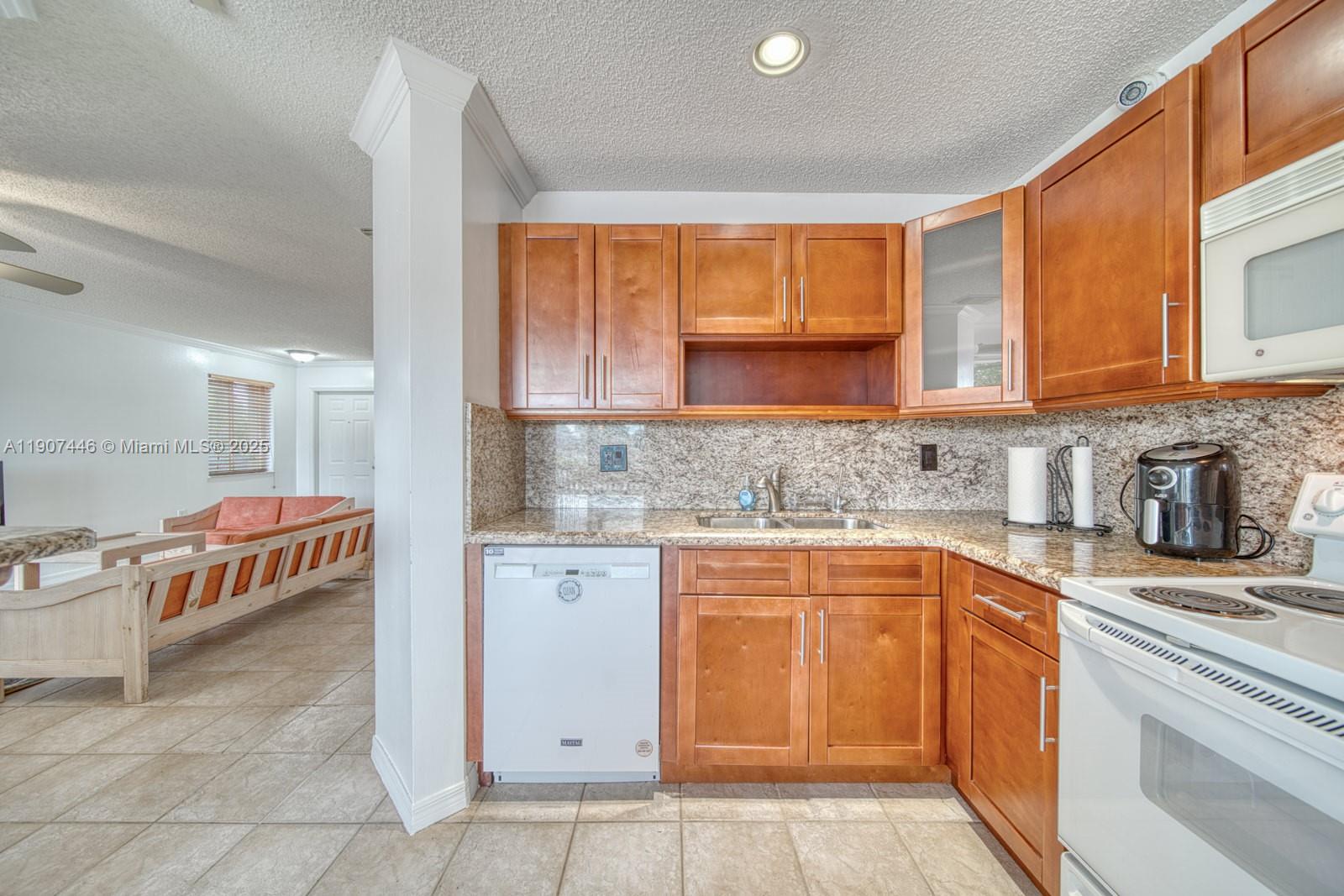 16394 Southwest 75th Street Miami, FL 33193 - Photo 13 of 35 a kitchen with stainless steel appliances granite countertop a stove a sink and a microwave