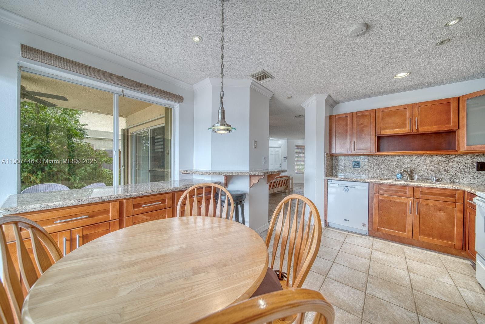 16394 Southwest 75th Street Miami, FL 33193 - Photo 14 of 35 a kitchen with stainless steel appliances granite countertop a sink a stove a dining table and chairs