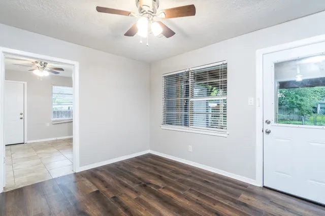 a view of an empty room with wooden floor and a window