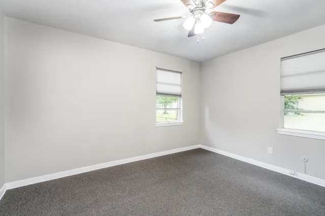 an empty room with a window and a fan