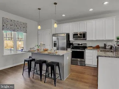 a kitchen with kitchen island granite countertop a stove a sink a oven a refrigerator and a dining table with wooden floor