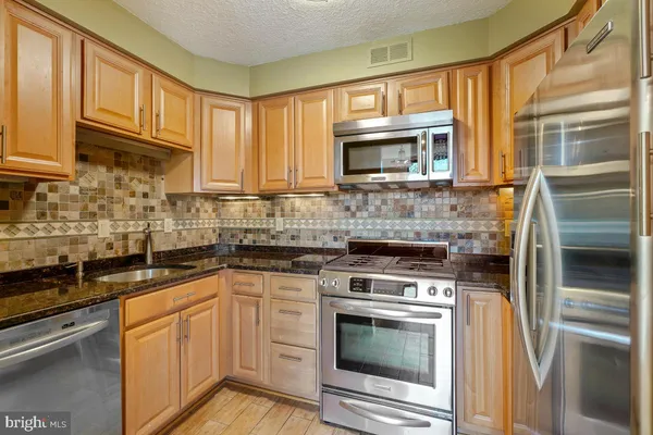 a kitchen with stainless steel appliances granite countertop a stove microwave and cabinets