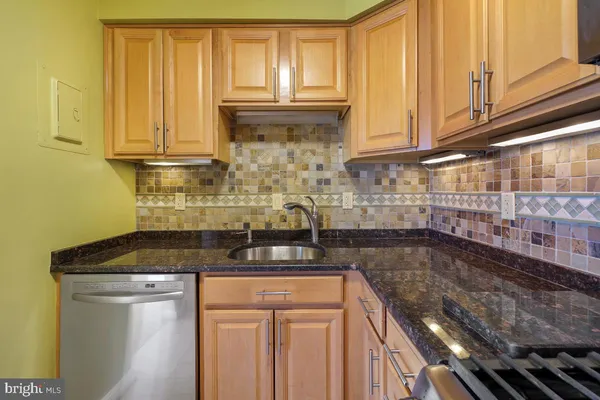 a kitchen with granite countertop a sink a stove and cabinets