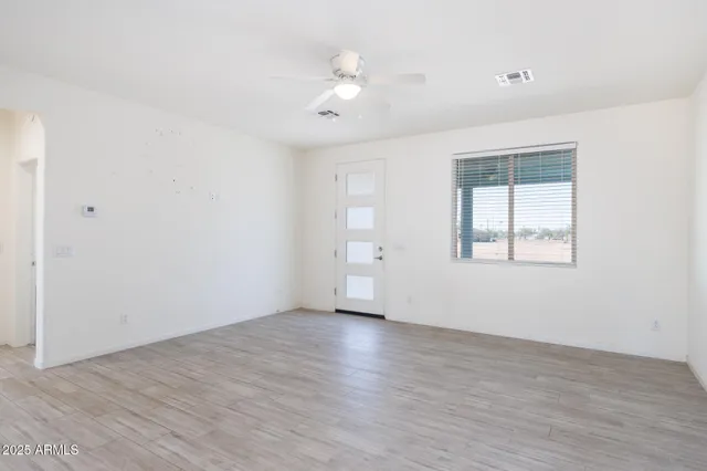 an empty room with wooden floor and a ceiling fan