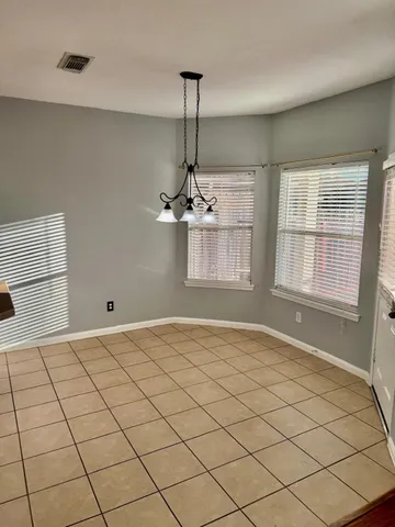 an empty room with wooden floor chandelier fan and windows