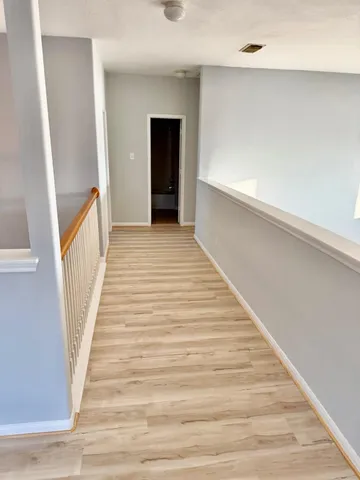 a view of a hallway with wooden floor and a chandelier