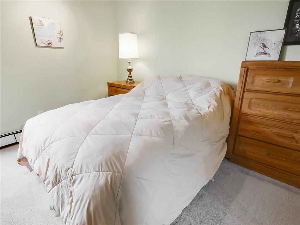 8100 Ryan Gulch Road, Unit E206 Silverthorne, CO 80498 - Photo 14 of 32 a bed sitting in a bedroom next to a lamp