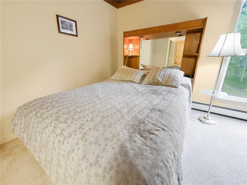 8100 Ryan Gulch Road, Unit E206 Silverthorne, CO 80498 - Photo 19 of 32 a large bed sitting in a bedroom next to a window