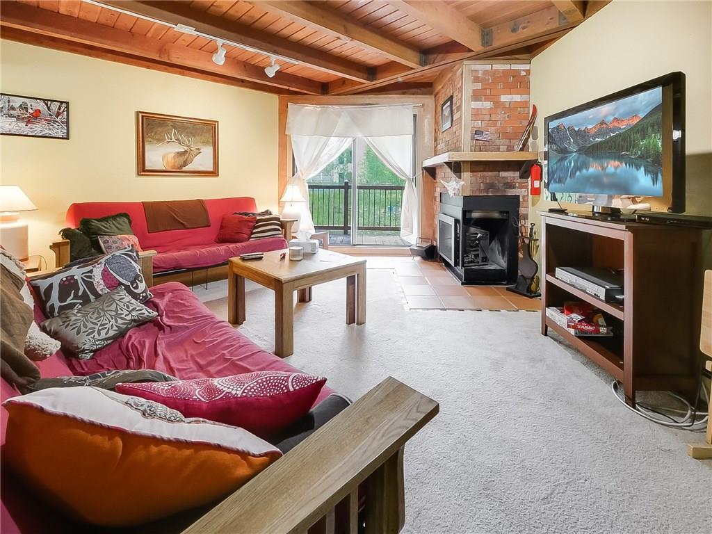 8100 Ryan Gulch Road, Unit E206 Silverthorne, CO 80498 - Photo 3 of 32 a living room with furniture a flat screen tv and a fireplace