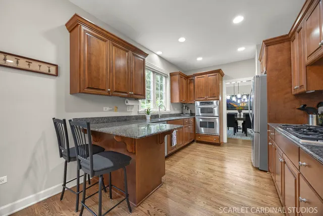 a kitchen with stainless steel appliances granite countertop wooden cabinets a refrigerator and a stove top oven
