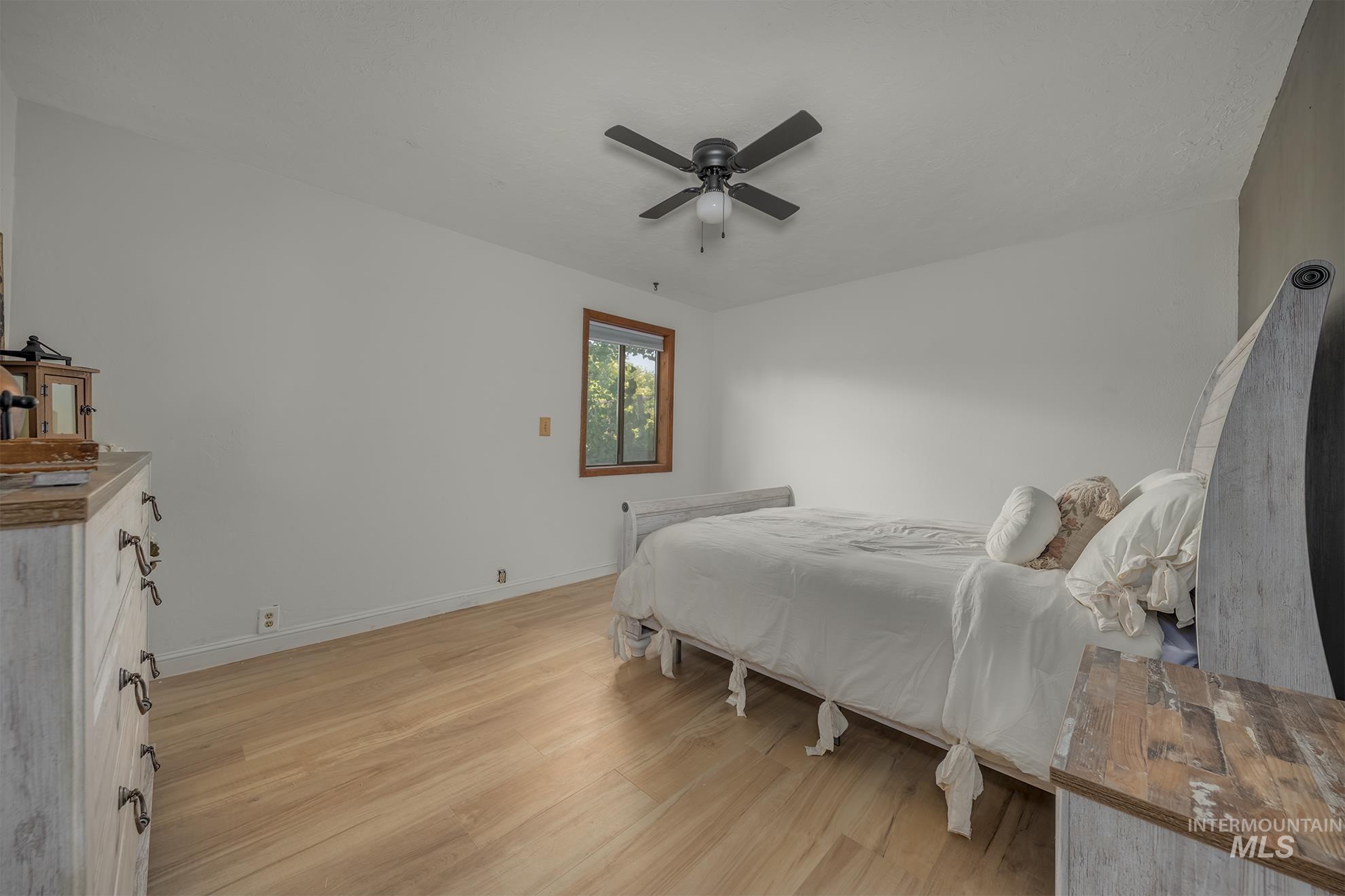61 Southwest 4th Street Ontario, OR 97914 - Photo 13 of 42 Spacious room featuring light wood-finish flooring, a window with natural wood trim, and a ceiling fan