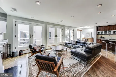 a living room with furniture large windows and wooden floor