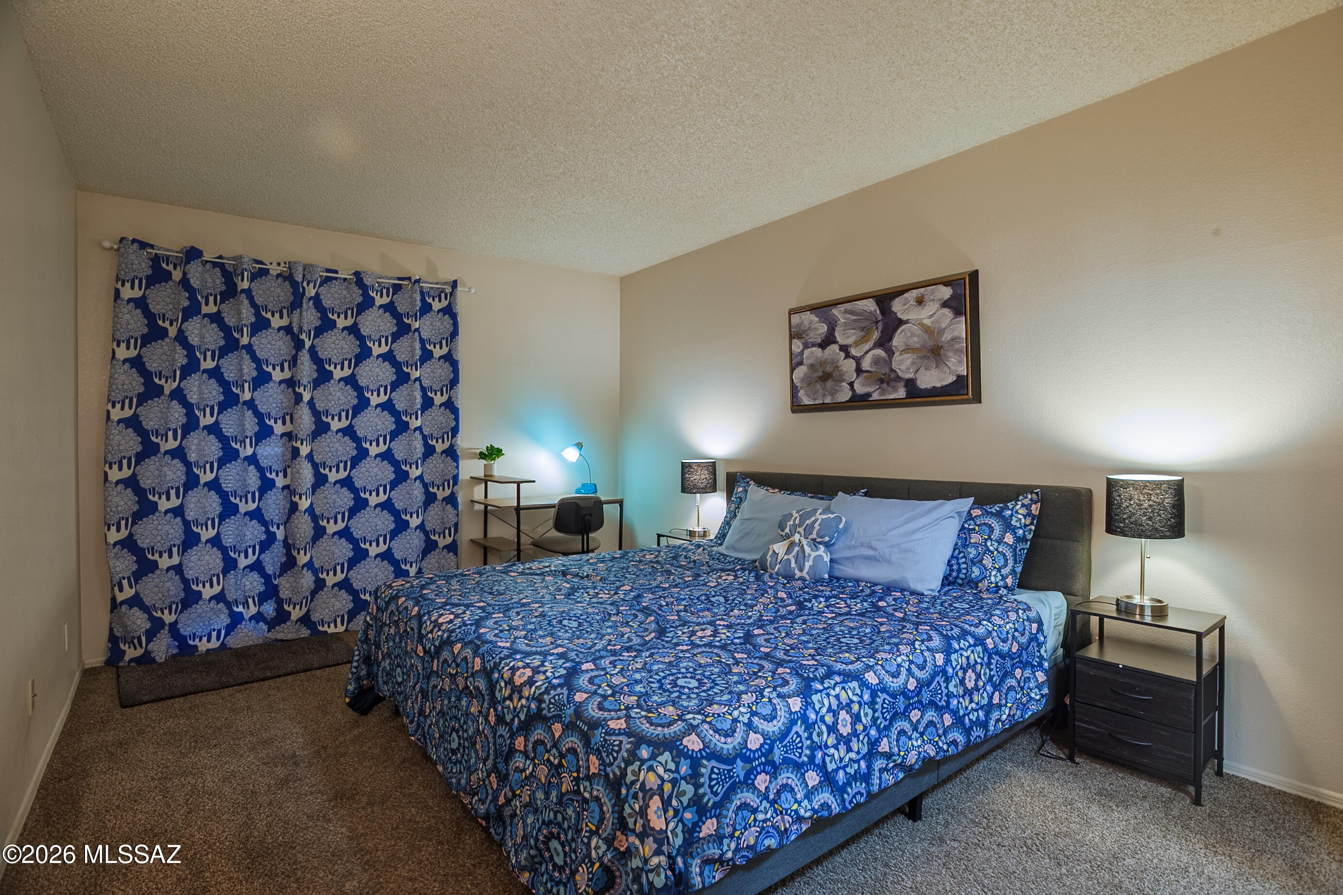 1200 East River Road, Unit B27 Tucson, AZ 85718 - Photo 23 of 40 a bed sitting in a bedroom next to a lamp