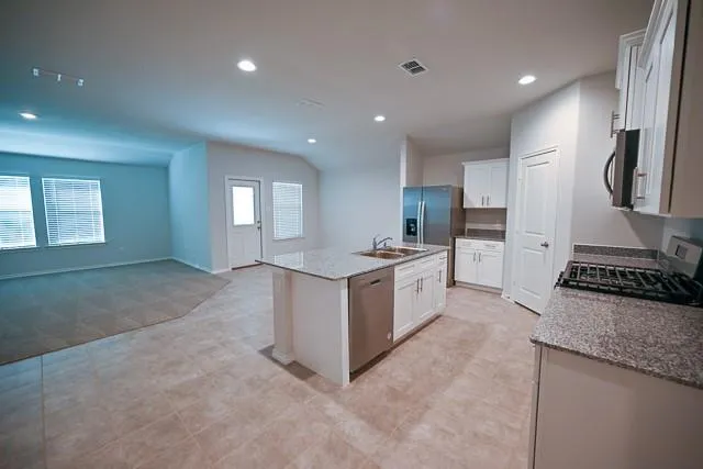 a large kitchen with stainless steel appliances granite countertop a stove a sink a refrigerator and white cabinets