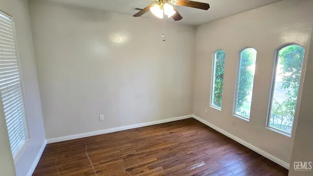 an empty room with wooden floor and fan