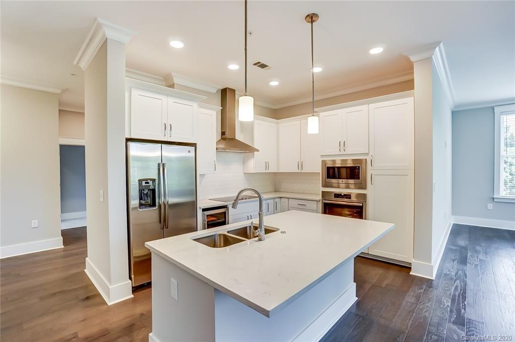830 Providence Road, Unit 303 Charlotte, NC 28207 - Photo 8 of 39 a kitchen with kitchen island a sink stainless steel appliances and wooden floor
