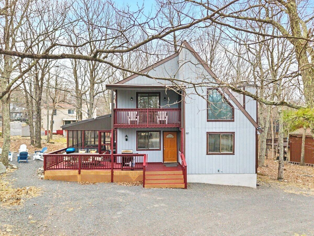a view of a white house with table and chairs under a large tree