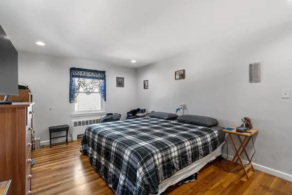 a bedroom with furniture a bed and a flat tv screen on the dresser