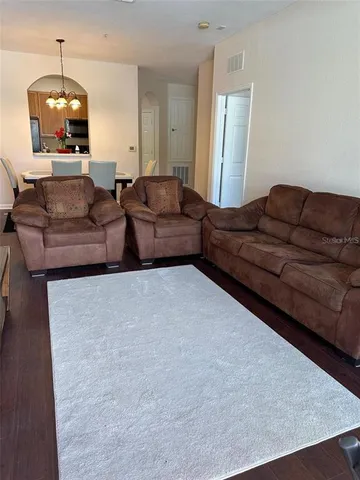 a living room with couches and a dining table with wooden floor