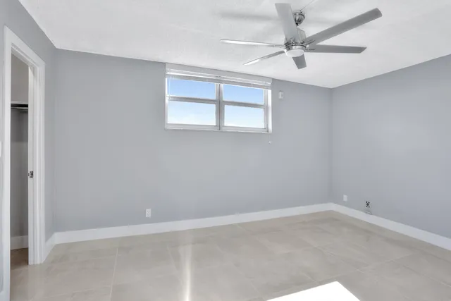 an empty room with a window and a fan