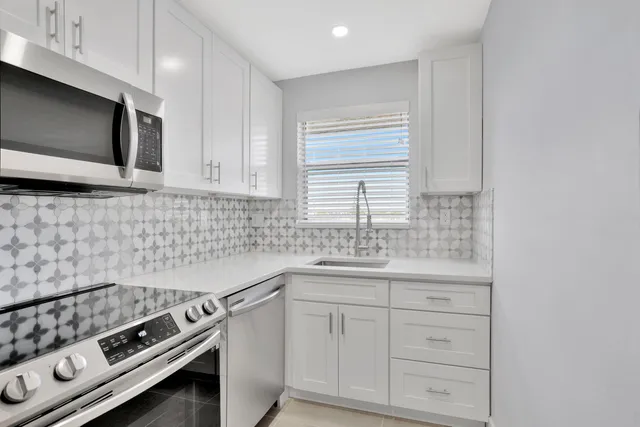 a kitchen with white cabinets stainless steel appliances and a sink