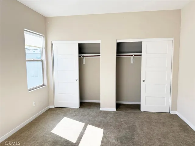 a view of an empty room with closet and a window