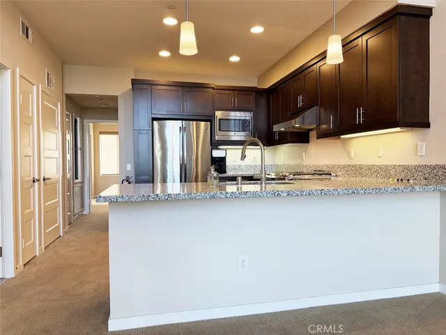 a kitchen with stainless steel appliances granite countertop a sink a stove and a refrigerator