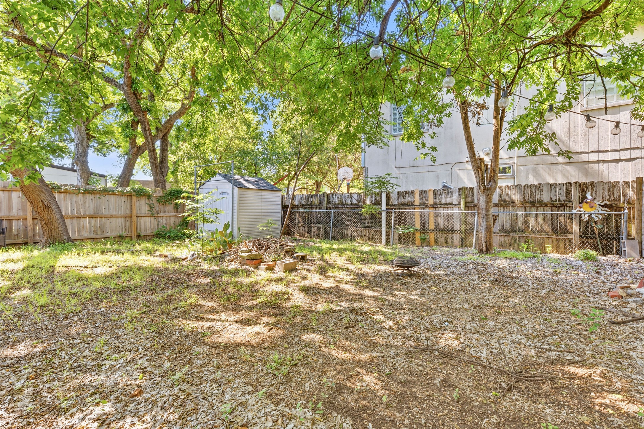 2207 Santa Rita Street Austin, TX 78702 - Photo 13 of 15 Expansive backyard featuring mature trees, a wooden privacy fence, a chain-link fence, and a storage shed